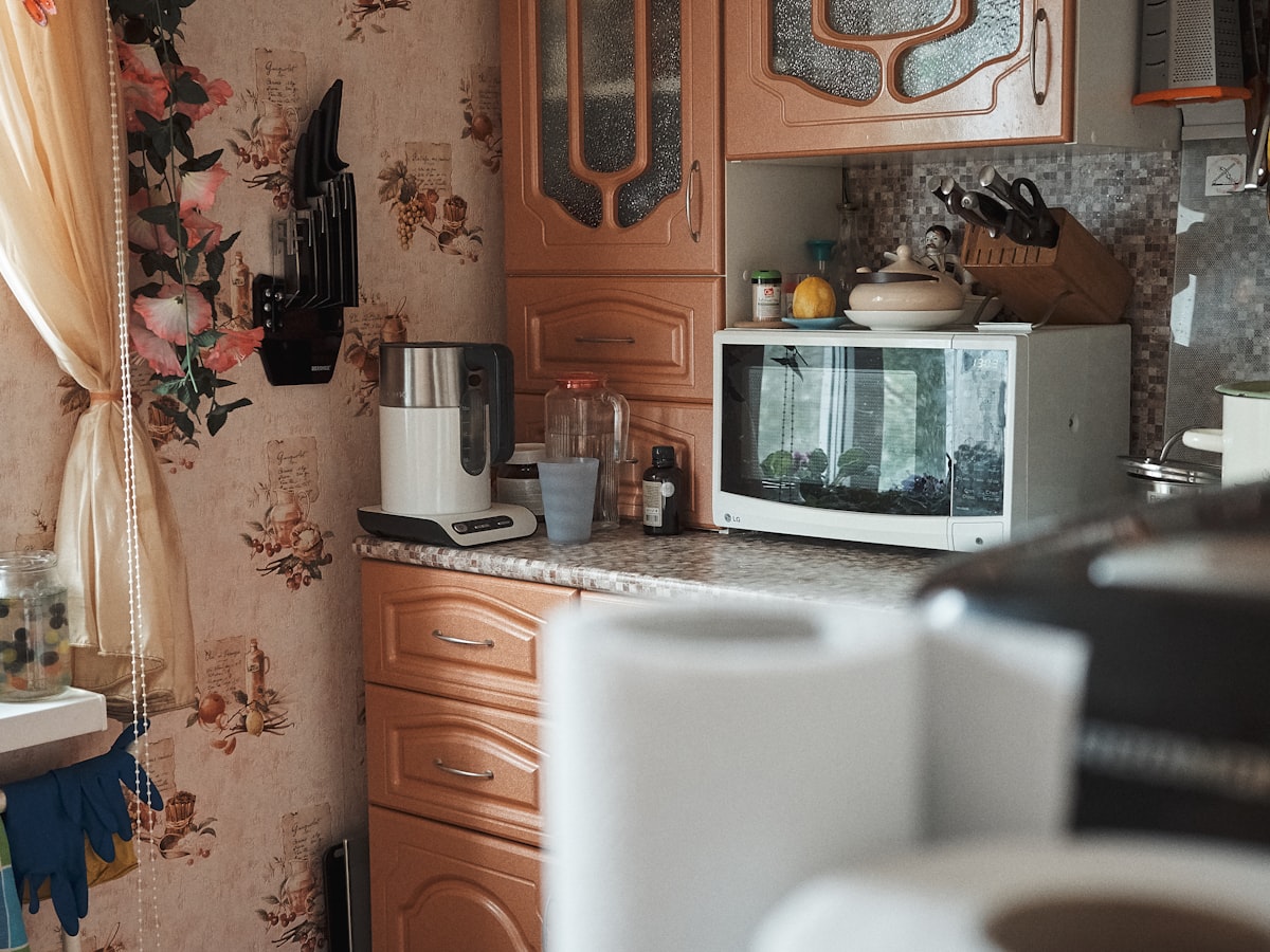 A white microwave oven on a kitchen cabinet
