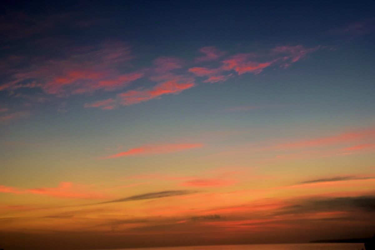 A colorful sunset sky with wispy clouds over calm water